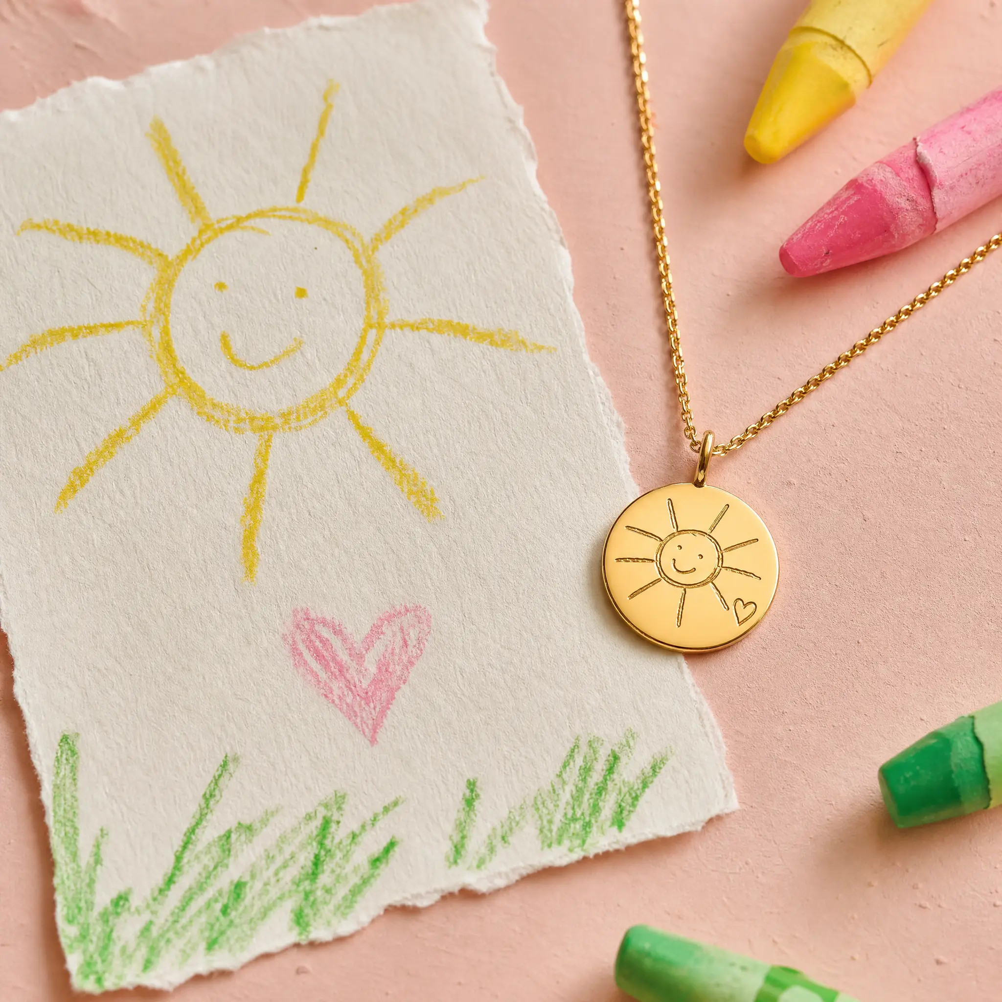 Illustrative concept showing a child's sun drawing beside a matching gold charm